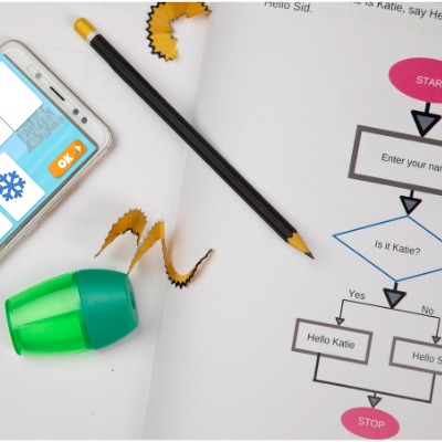 Flat-lay of a phone, pencil, sharpener, and an open Brainologi activity book