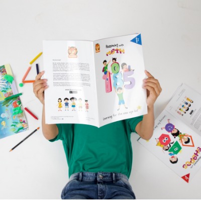 A child engaged in reading and activity with a Brainologi book